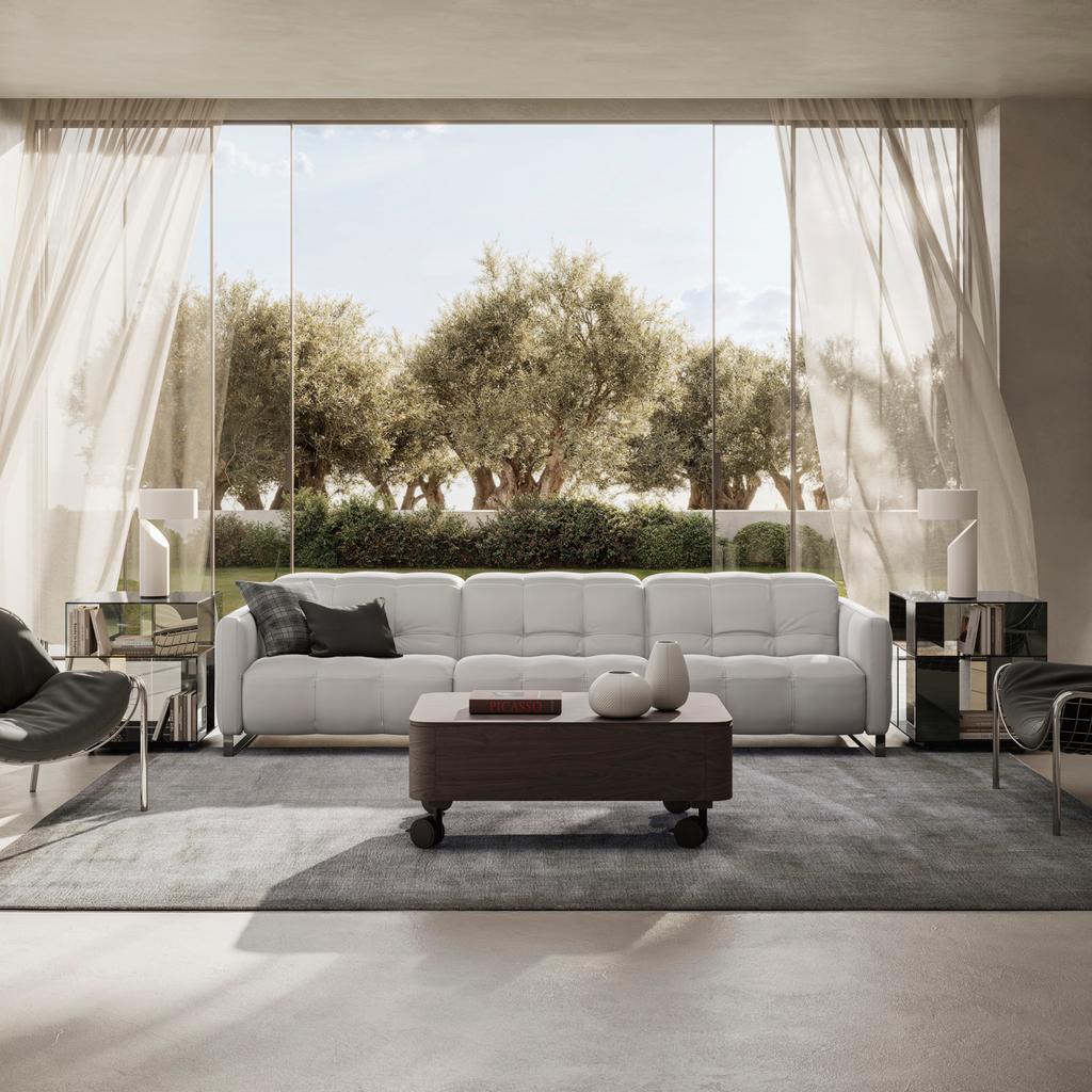 The Fero sofa, known as the Natuzzi Philo, is a contemporary Italian-designed leather sofa featuring soft, deep cushioning and a refined, minimalist silhouette. Shown here in a bright, modern living room with floor-to-ceiling windows, the white sofa is st