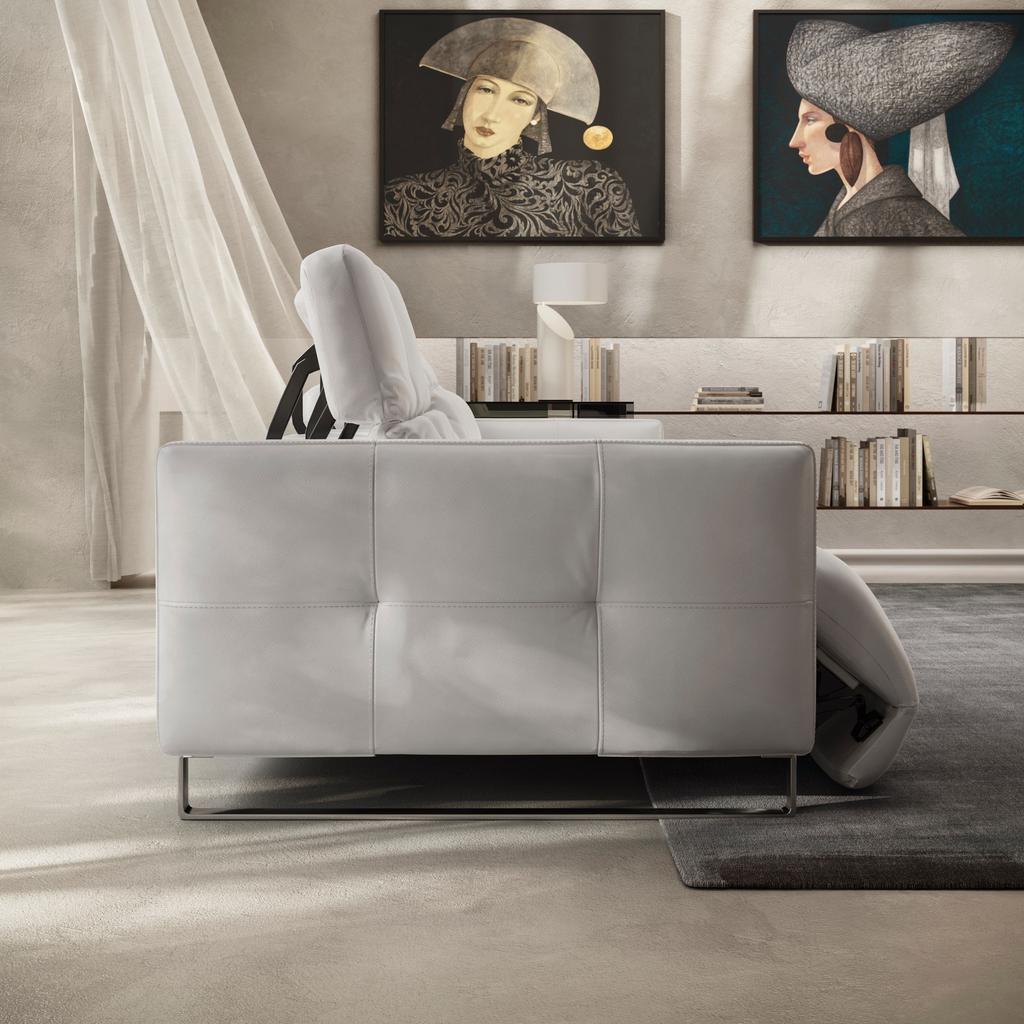 Side profile of the Fero sofa, known as the Natuzzi Philo, showcasing its adjustable headrest and reclining functionality. Upholstered in premium white leather, the design features structured cushioning and slim metal legs, combining modern Italian stylin