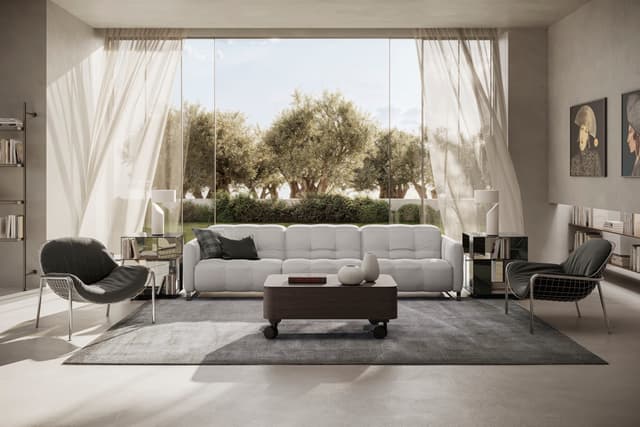 The Fero sofa, known as the Natuzzi Philo, is a contemporary Italian-designed leather sofa featuring soft, deep cushioning and a refined, minimalist silhouette. Shown here in a bright, modern living room with floor-to-ceiling windows, the white sofa is st