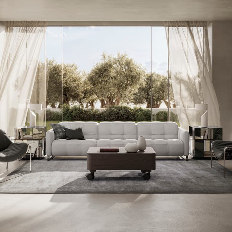 The Fero sofa, known as the Natuzzi Philo, is a contemporary Italian-designed leather sofa featuring soft, deep cushioning and a refined, minimalist silhouette. Shown here in a bright, modern living room with floor-to-ceiling windows, the white sofa is st